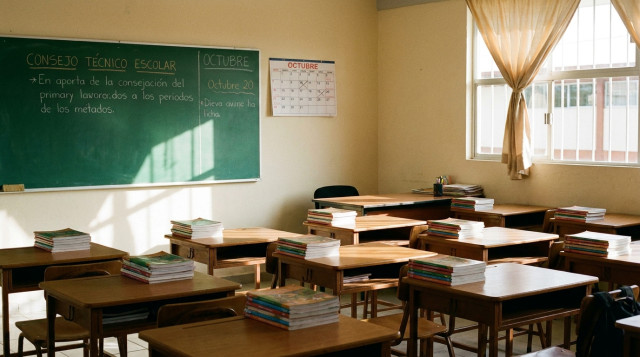 Aula escolar de primaria vacía con libros ordenados y pizarrón informativo sobre el Consejo Técnico Escolar de octubre
