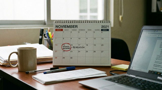 calendario de pared de noviembre con el lunes 16 marcado como descanso por el puente de noviembre sobre un escritorio de oficina