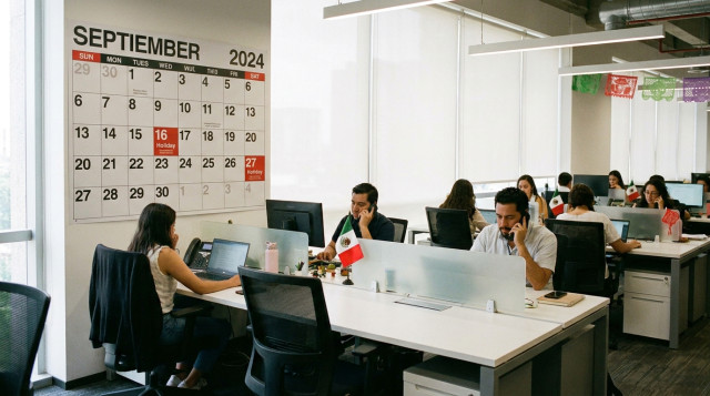 Empleados trabajando en una oficina moderna durante un día festivo oficial con el calendario nacional al fondo