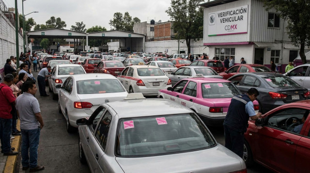 linea de autos esperando en un centro de verificacion vehicular oficial de la cdmx con engomado rosa en el medallon